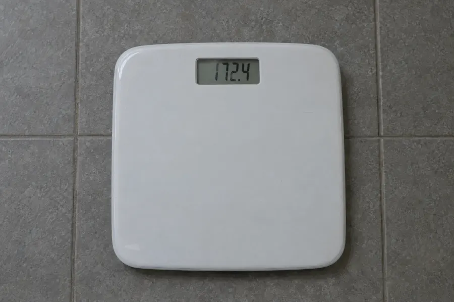 A basic white bathroom scale showing 172.4